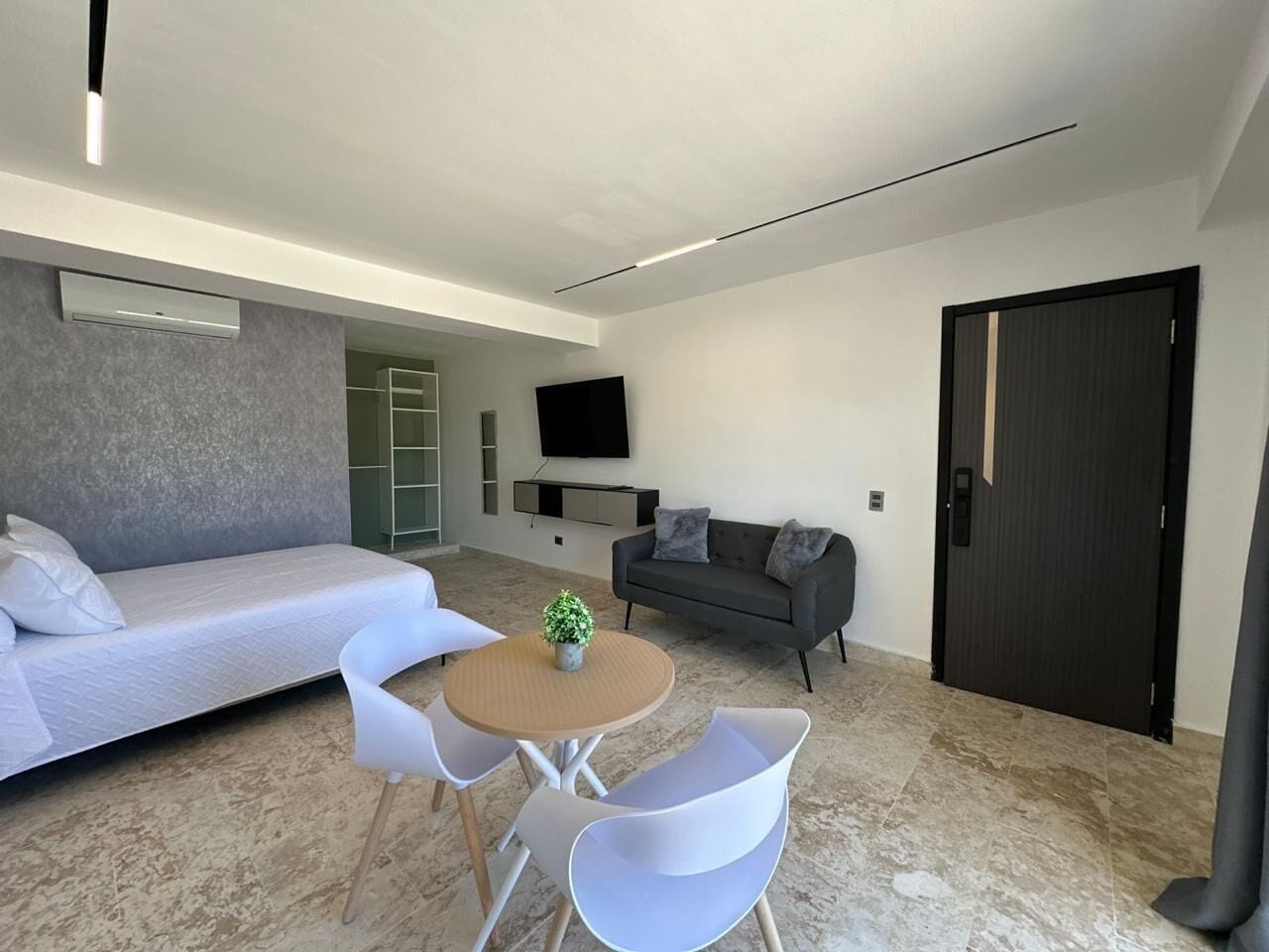 Une chambre moderne équipée d’un lit, d’un canapé, d’une télévision et d’une petite table avec des chaises.