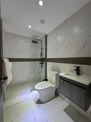 Een moderne badkamer met douche, toilet en wastafel.