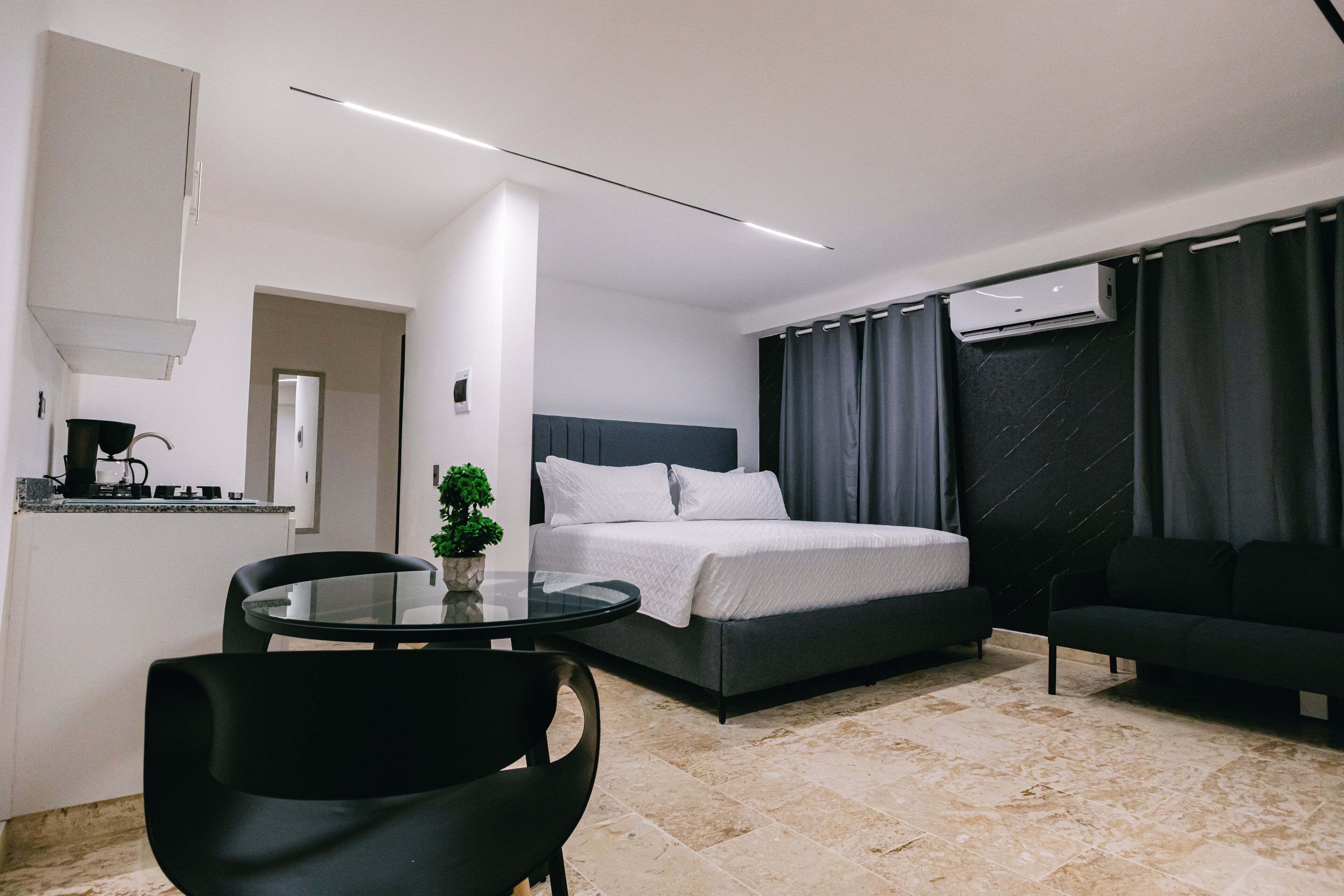 Une chambre à coucher moderne comprenant un lit, un canapé, une table à manger et un petit coin cuisine.