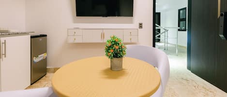 Una cocina moderna con refrigerador integrado, un televisor de pantalla plana sobre la encimera y una pequeña planta en maceta sobre una mesa redonda.
