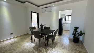 A dining area with a table and chairs, an air conditioning unit, and a potted plant.
