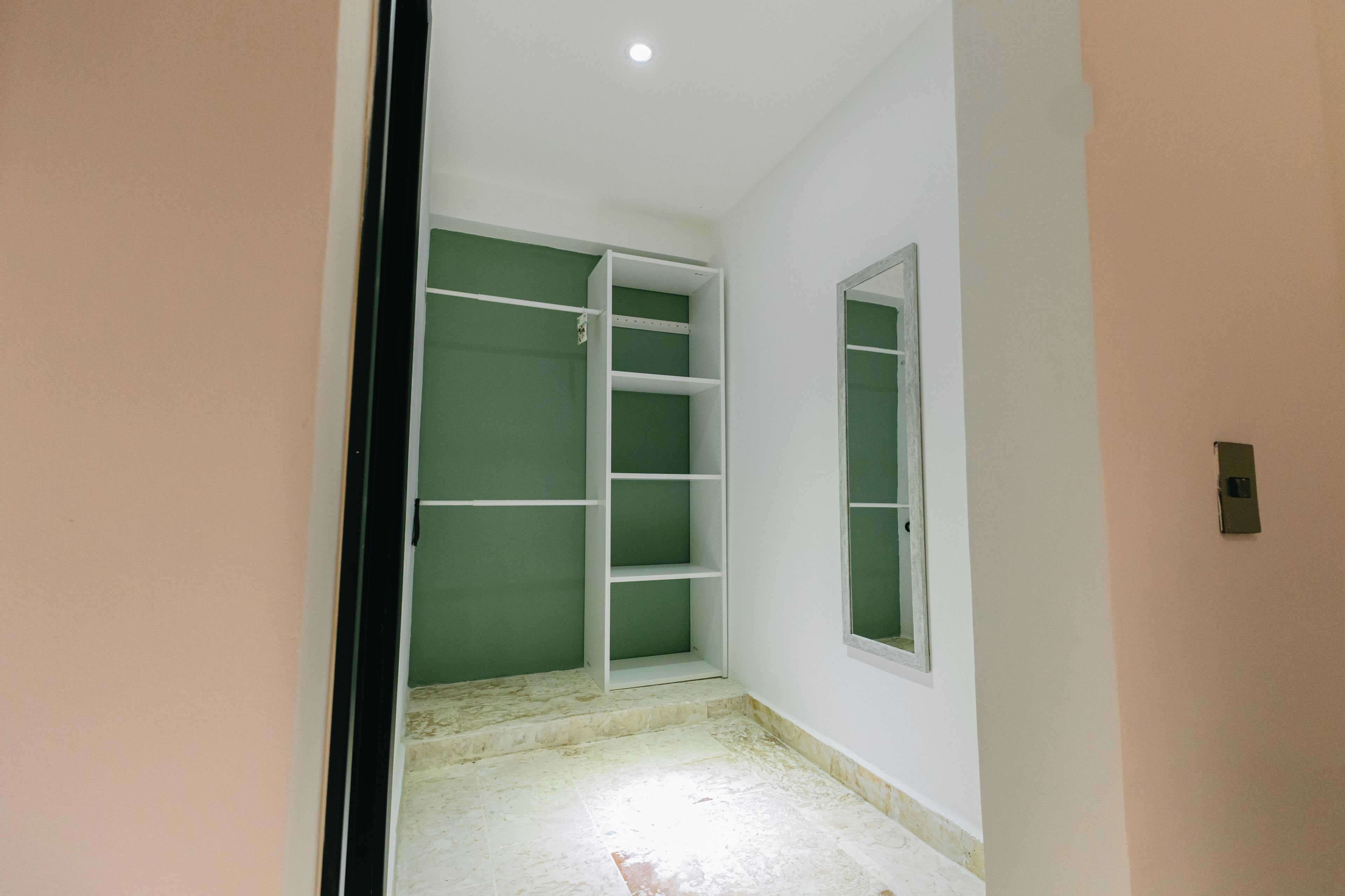 Een gang met een groene muur, een witte deur en een witte schapunit.