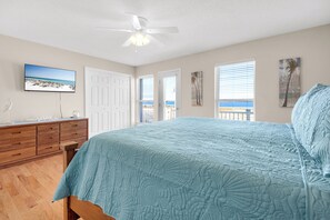 A bedroom with a bed, a ceiling fan, a TV, and a view of the ocean through the windows. - Sound-View Beach Retreat w/ Multiple Decks, Kayaks & Bikes  Island Vibes (Navarre)