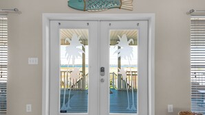 A double door with frosted glass panels, a white frame, and a decorative fish hanging above. - Sound-View Beach Retreat w/ Multiple Decks, Kayaks & Bikes  Island Vibes (Navarre)