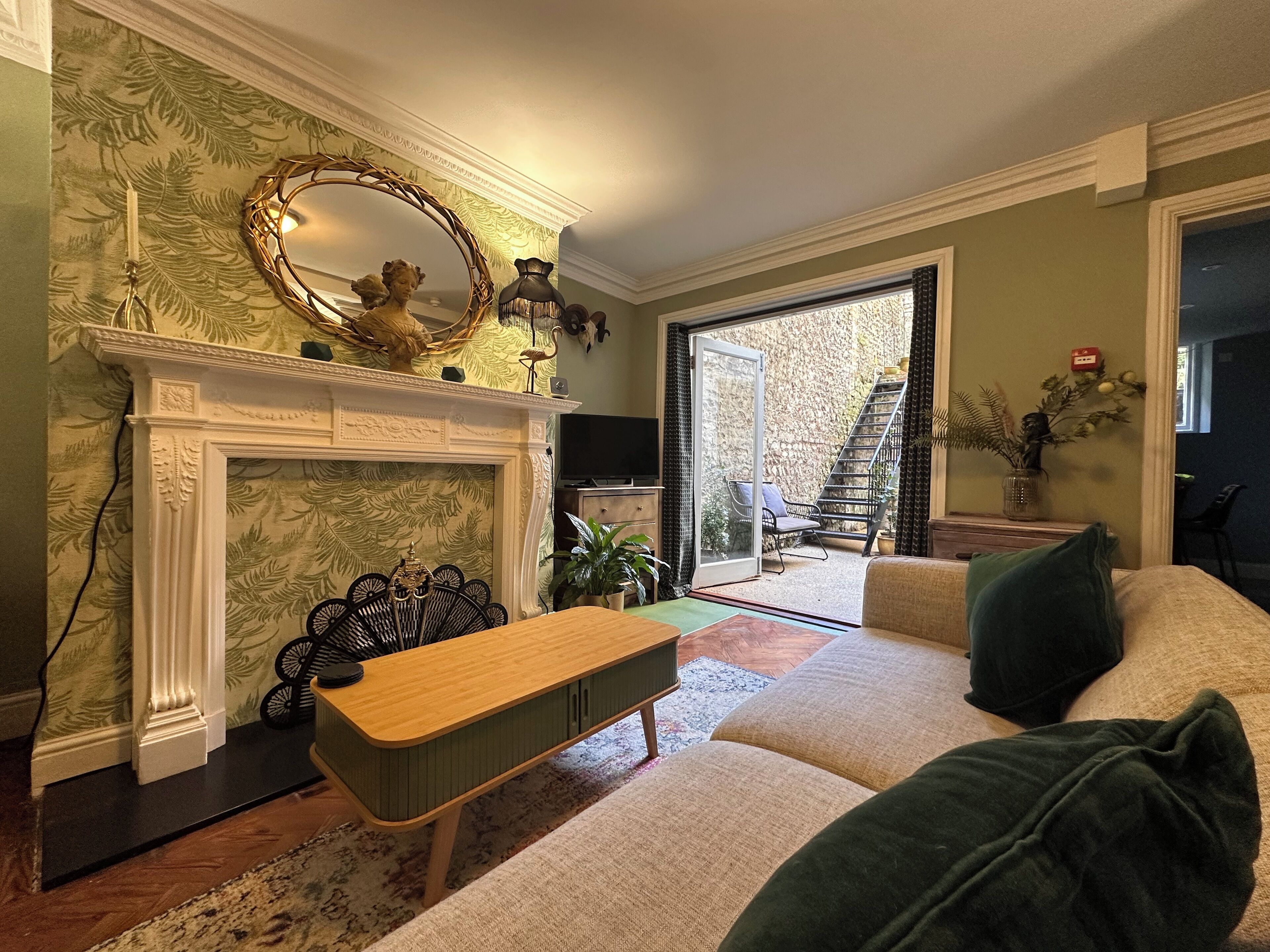 A living room with a fireplace, a sofa, a coffee table, and a view of the outside.