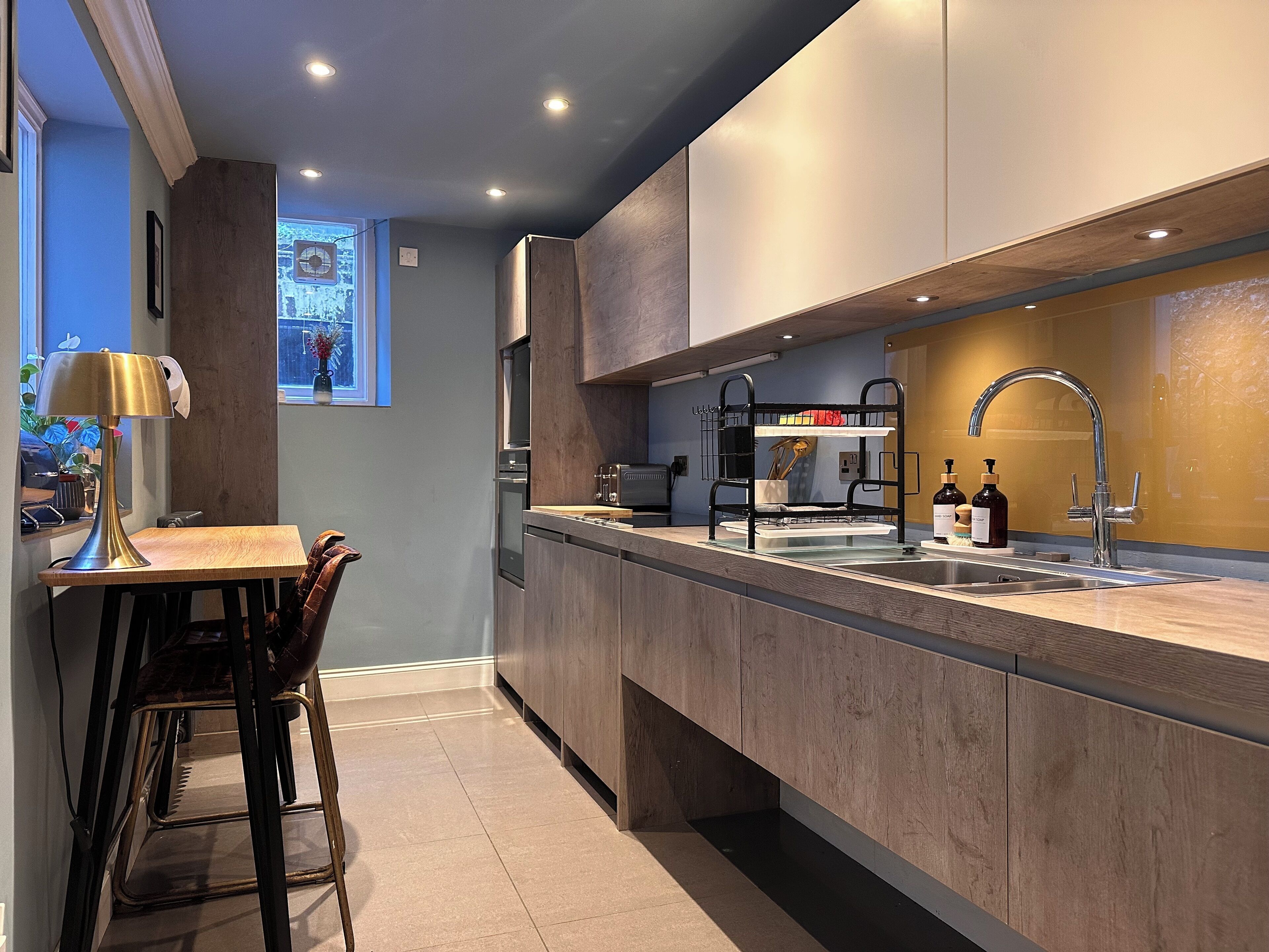 A modern kitchen with a wooden countertop, stainless steel sink, and a built-in oven.