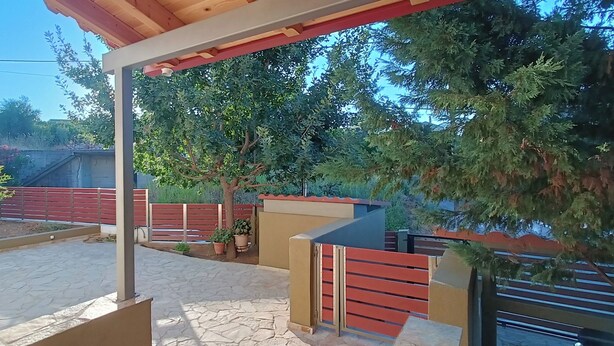 A covered outdoor area with a stone floor, wooden benches, and a metal gate. - Cosy, fully equipped 3 bedroom villa, near Kalamata that will steal your heart! (Messini)