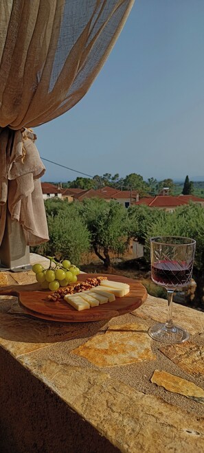 A table with a cheese board, grapes, walnuts, and a glass of red wine.