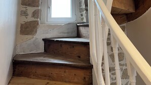 A wooden staircase with a stone wall and a window. - Crozon-Morgat: Renovated family home for 6-8 people 5 minutes from the beach (Crozon)