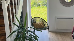 A staircase with white railings, a potted plant, a wicker chair with a polka-dotted cushion, and a view of greenery outside. - Crozon-Morgat: Renovated family home for 6-8 people 5 minutes from the beach (Crozon)