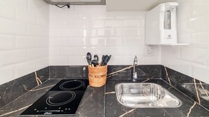 A modern kitchen with a black marble countertop, a built-in stove, a sink, and a white tiled backsplash. - Ape Novo ao lado do Bourbon e Allianz. (São Paulo)