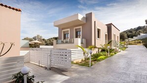 Une maison moderne à deux étages, dotée d’un balcon, d’une allée pavée et d’une clôture blanche.