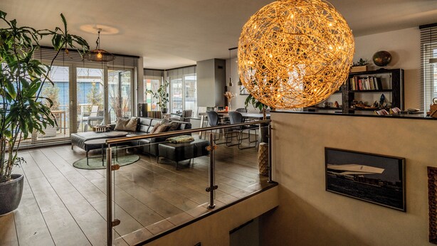 A modern living room with a large sofa, a dining area, and a staircase. - Nova Houseboat Deluxe + free bikes (Amsterdam)