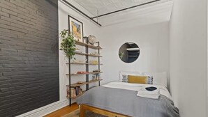 Ein modernes Schlafzimmer mit einem Bett, einem runden Spiegel, einem Bücherregal und einem Blumentopf.