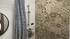 Un baño con ducha, inodoro y espejo.