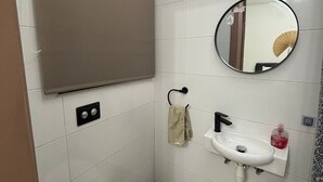 Un baño pequeño con inodoro, lavamanos y espejo.
