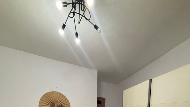 Un dormitorio moderno con una cama grande, un ventilador decorativo en la pared y una lámpara en el techo.