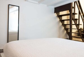 Un dormitorio con cama, un espejo grande y una escalera de madera.