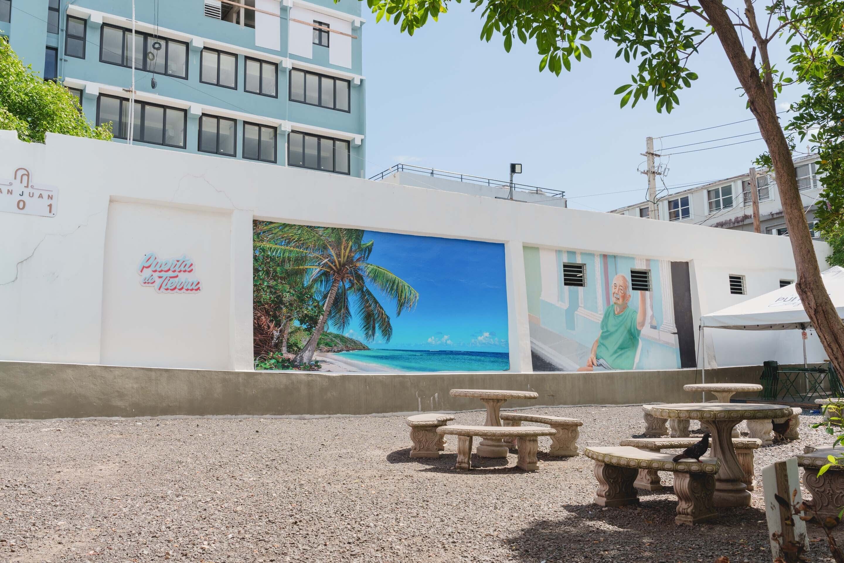 A building with a mural of a beach scene, outdoor seating, and a sign that reads 'Puerto Rico.'