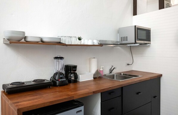 A kitchen with a microwave, a blender, a coffee maker, and a sink.