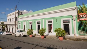 A two-story building with a green facade, a white balcony, and a sign for a restaurant on the ground floor. - Elokut Apartments by Stay with Bear (San Juan)