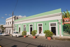 Un edificio de dos pisos con fachada verde, un balcón blanco y un letrero de restaurante en la planta baja.