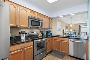 A modern kitchen with wooden cabinets, stainless steel appliances, and a dishwasher. - 🌞🌴Walk to the Beach | Balcony Views | Costa Vista Townhouse #2🌴🌞 (Miramar Beach)