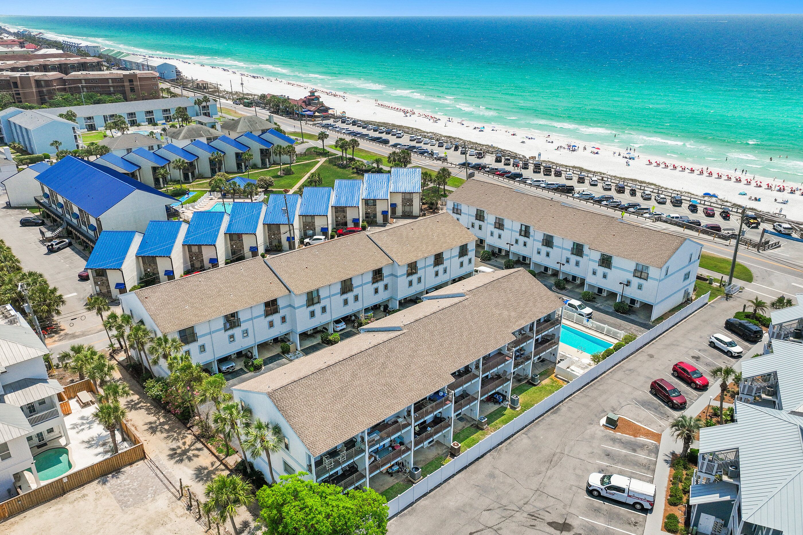 A hotel with multiple floors, a swimming pool, and a beach view.