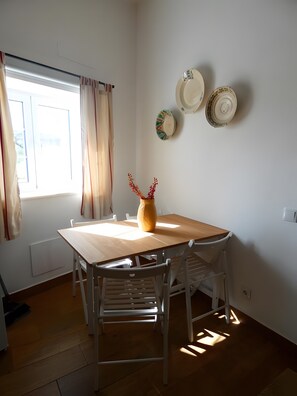 Ein Essbereich mit Holztisch, weißen Stühlen, einer Vase mit Zweigen und an der Wand befestigten Tellern.