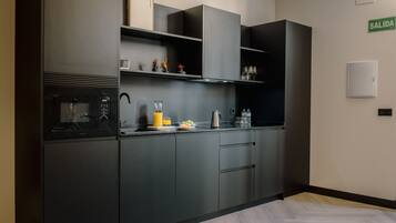 Een magnetron, een broodrooster, kookgerei, borden en bestek, eettafels