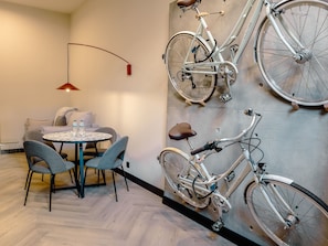 Een moderne kamer met een ronde tafel, twee stoelen, een aan de muur bevestigd fiets en een hanglamp.