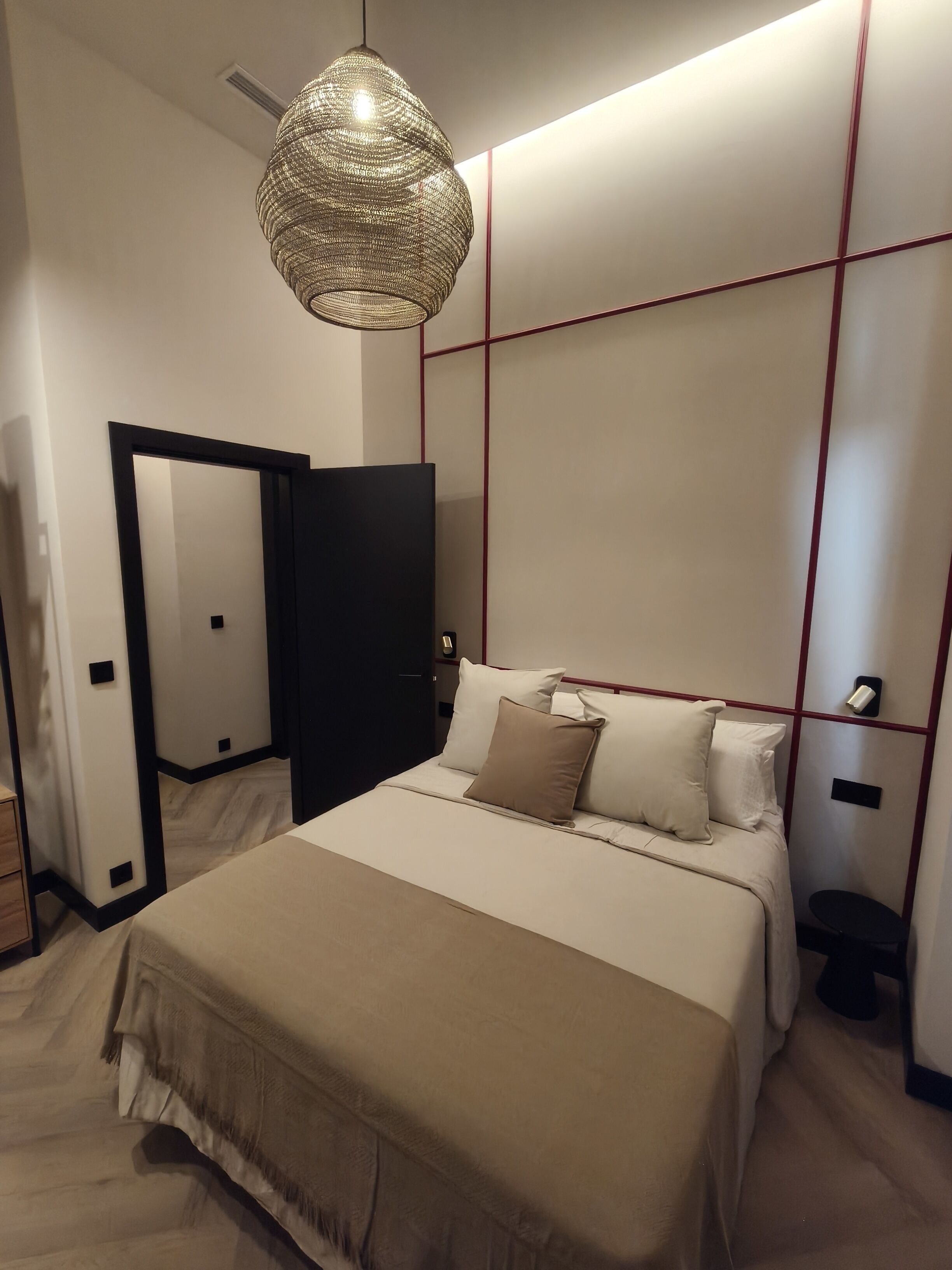 A modern bedroom with a large bed, a hanging light fixture, and a wardrobe.