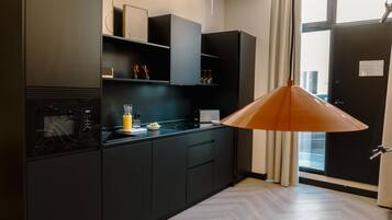 Een magnetron, een broodrooster, kookgerei, borden en bestek, eettafels