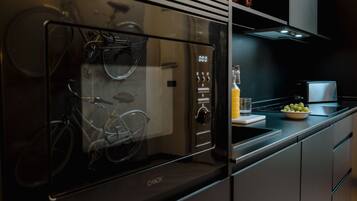 Una cocina moderna con horno empotrado, refrigerador con puerta de vidrio y una bicicleta en su interior.