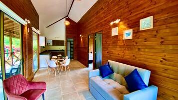A modern interior with wooden walls, a sofa, a red chair, and a dining area.