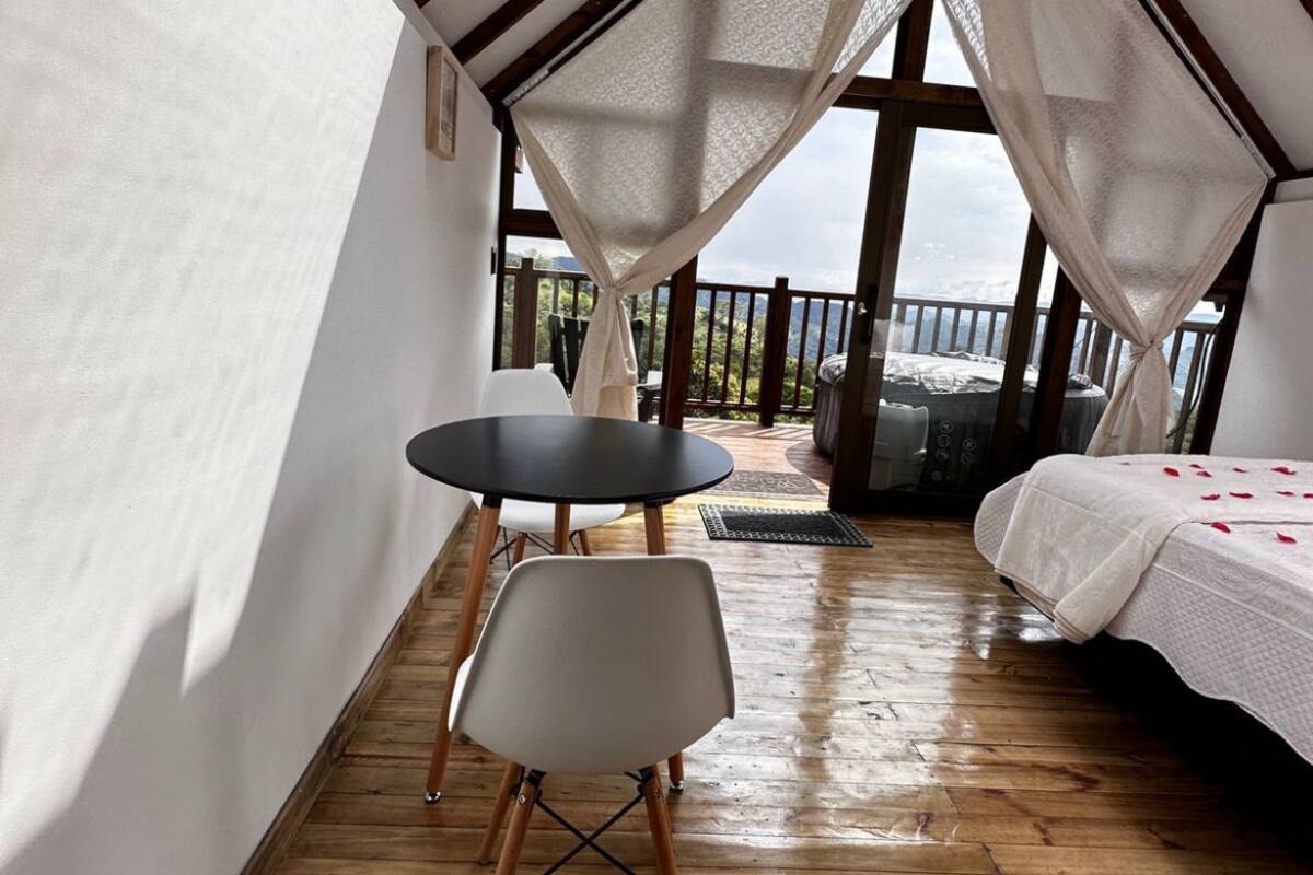 A cozy attic bedroom with a wooden floor, a bed, a table, and a chair.