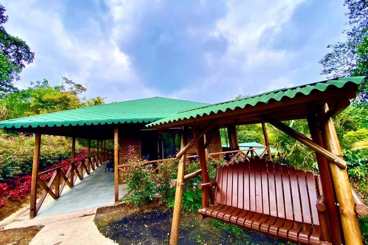 A wooden structure with a green roof, a bench, and a staircase leading to a building.
