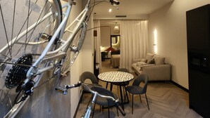 A modern living room with a bicycle mounted on the wall, a dining area with a round table and chairs, and a kitchen area visible through an open door. - Ginkgo Biloba - Inner Calmness (Badajoz)