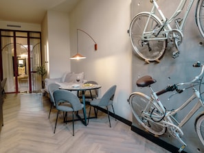 Un interior modern amb zona de dinar, una bicicleta blanca i un suport de bicicleta fixat a la paret.