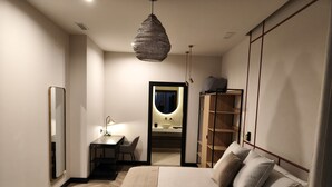 Une chambre à coucher moderne comprenant un lit, une table de chevet, une lampe, une armoire et un miroir qui reflète une salle de bain.