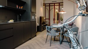 Une cuisine moderne avec des meubles de couleur sombre, un four à micro-ondes et un coin repas agrémenté d’un vélo.