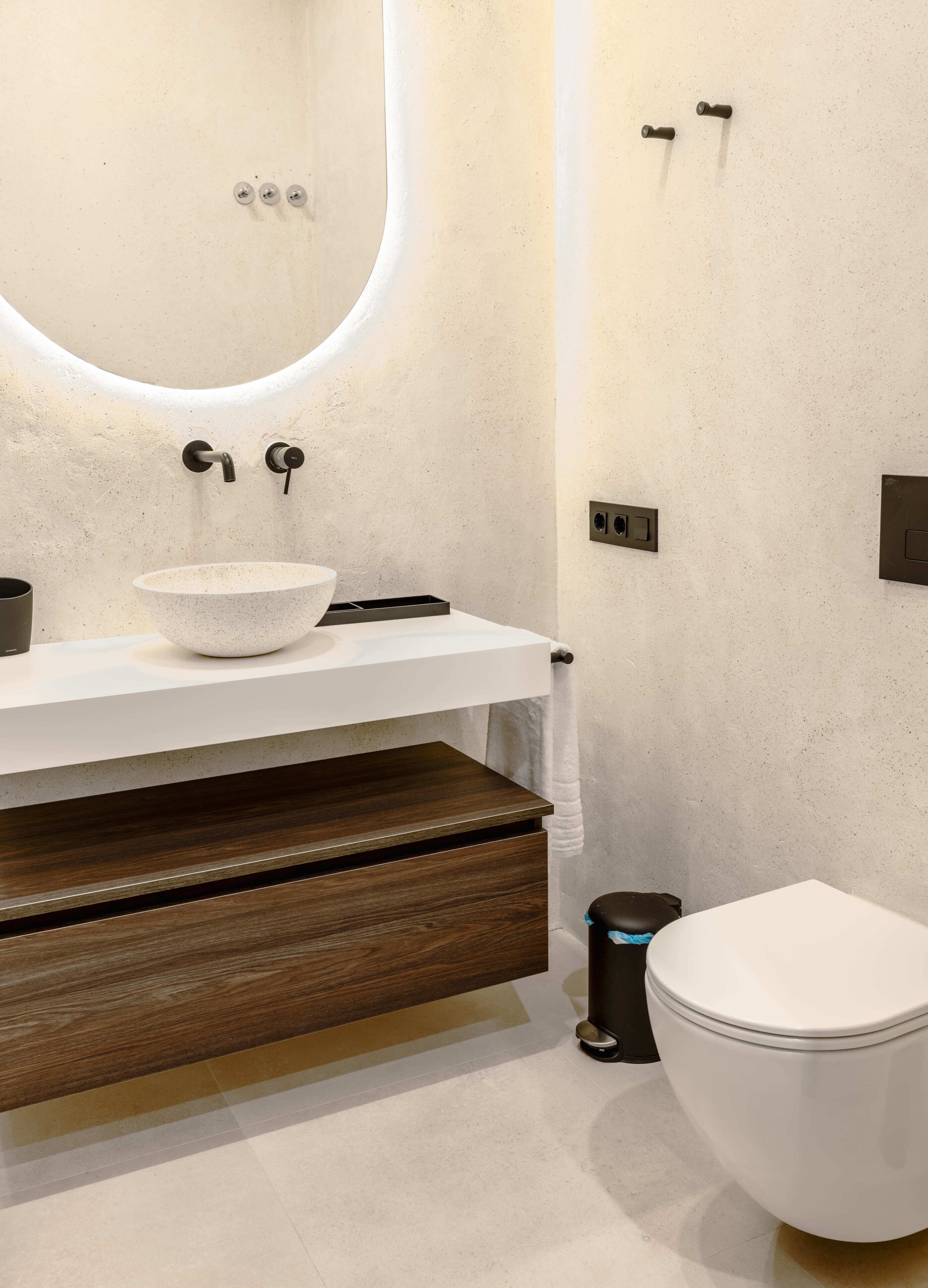 Ein modernes Badezimmer mit einem weißen Waschbecken, einer Holzausstattung und einer weißen Toilette.