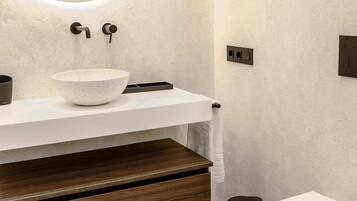 Ein modernes Badezimmer mit einem weißen Waschbecken, einer Holzausstattung und einer weißen Toilette.