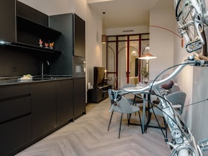 Una cocina moderna con armarios oscuros, un microondas y una zona de comedor con una bicicleta.