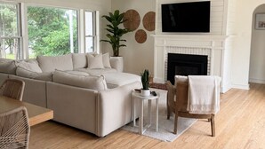 A spacious living room with a large sofa, a fireplace, a television, and a dining area with a table and chairs. - Beautiful 3-bedroom house minutes from Swarthmore! (Morton)