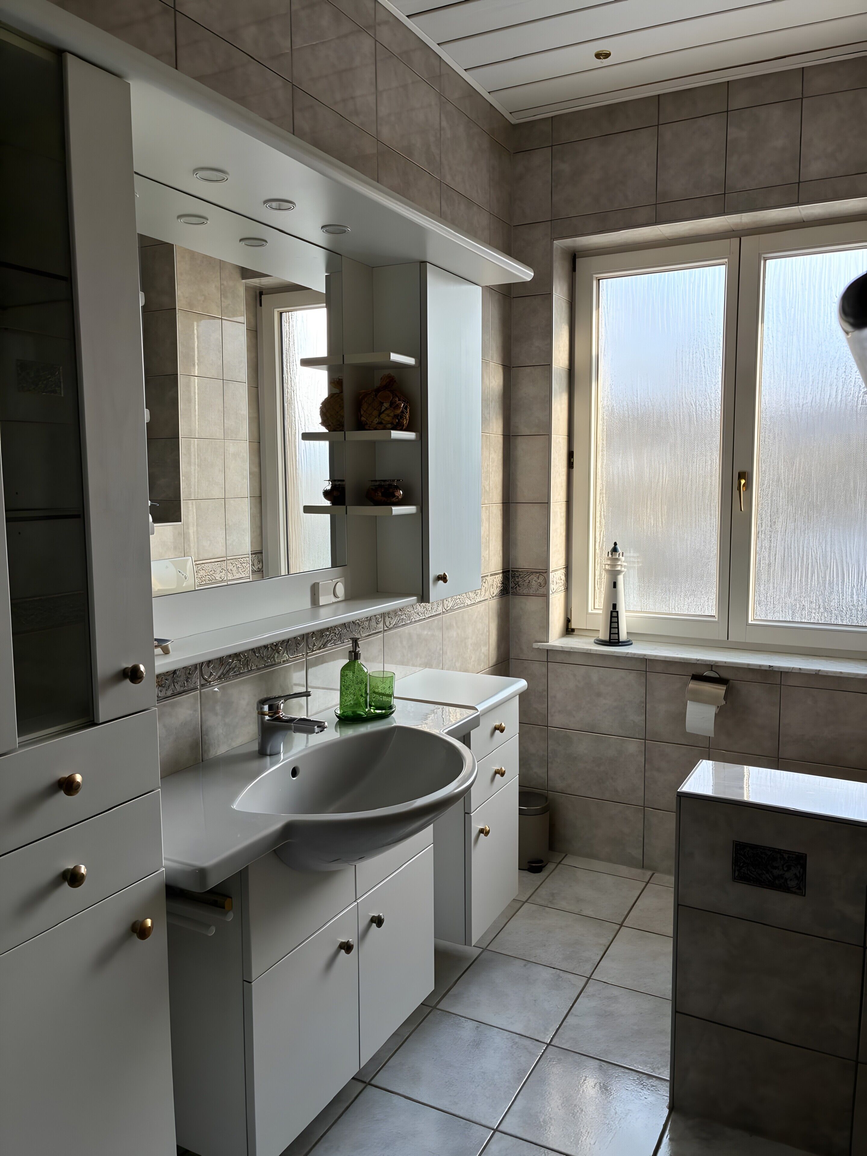 Un baño moderno con un espejo grande, un lavabo y una ventana.