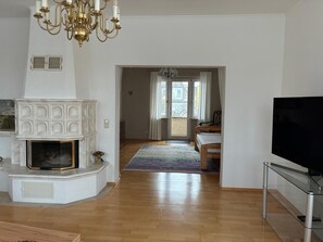 Una sala de estar con chimenea, televisor y vista a través de una puerta.