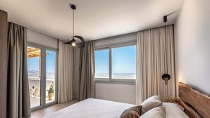 Une chambre avec un grand lit, une vue sur la ville et un balcon.