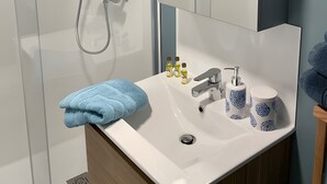 A modern bathroom with a glass-enclosed shower, a white sink with blue-patterned cups, and a mirror above the sink. - Holiday Home “Le Pentadou – Gîte Lou Costalou” with Pool, Private Terrace & Wi-Fi (Felzins)