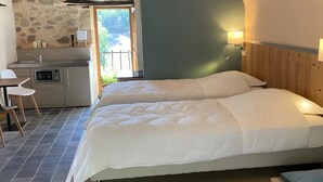 A bedroom with a bed, a built-in desk, a stone wall, and a view of the outdoors. - Holiday Home “Le Pentadou – Gîte Lou Costalou” with Pool, Private Terrace & Wi-Fi (Felzins)